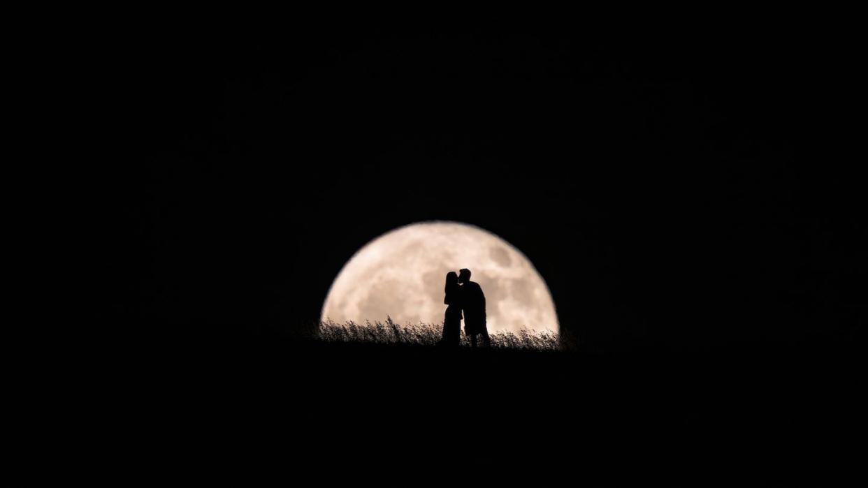 romance under the moon, an enamored kiss illuminated by the full moon