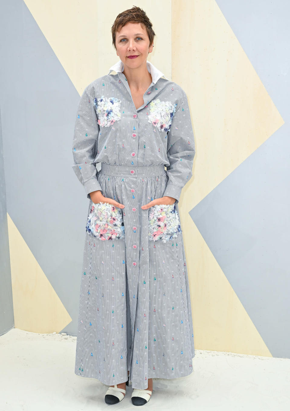 <p>Maggie Gyllenhaal wears a floor-length button-down dress at the Chanel presentation. The dress has pops of color on the buttons and pockets for an added bit of flair.</p>