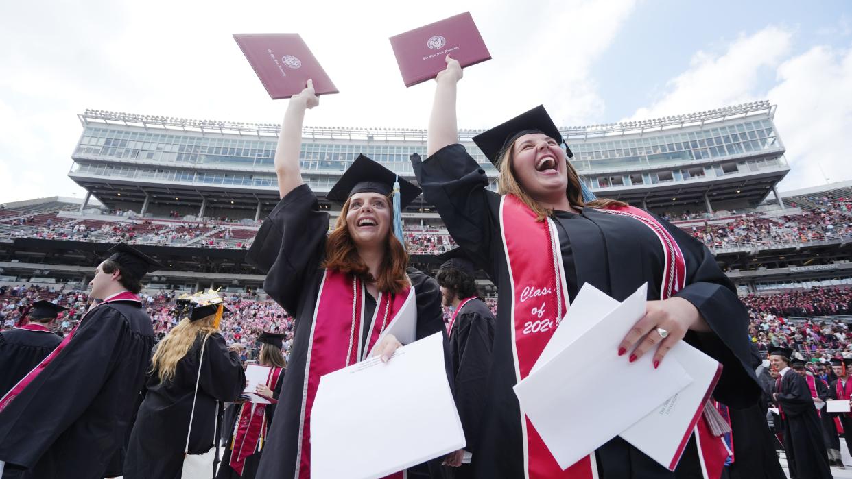 Caroline Castrucci (left) and Alexandra Criss look to Criss' father moments after earning their degrees from the College of Education and Human Resources during the Ohio State Spring 2024 Commencement held Sunday, May 5, 2024 in Ohio Stadium.