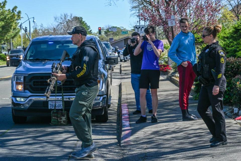 Officers return to their vehicle as bystanders watch during a standoff at the Hazel Ranch apartment complex in the 8800 block of Winding Way in Fair Oaks on Friday. They were retrieving water for other officers at the scene. Renée C. Byer/rbyer@sacbee.com