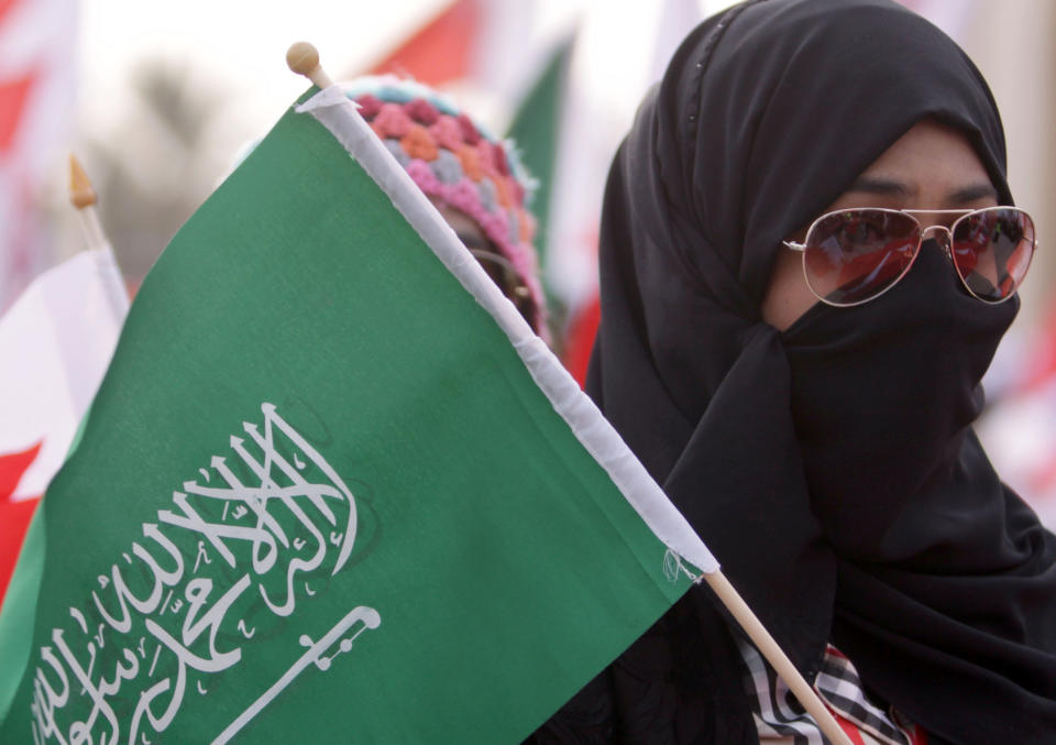 In a photo taken on Feb. 11, 2012, government supporters participating in a demonstration wave red-and-white Bahraini flags and green Saudi flags at Bahrain's Grand Mosque in Manama, Bahrain. During a sermon last week at Bahrain's Grand Mosque, the pro-government prayer leader offered sweeping praise to one of the Arab Spring's counter revolutions: Gulf rulers bonding together against dissent with powerful Saudi Arabia as their main guardian. (AP Photo/Hasan Jamali)