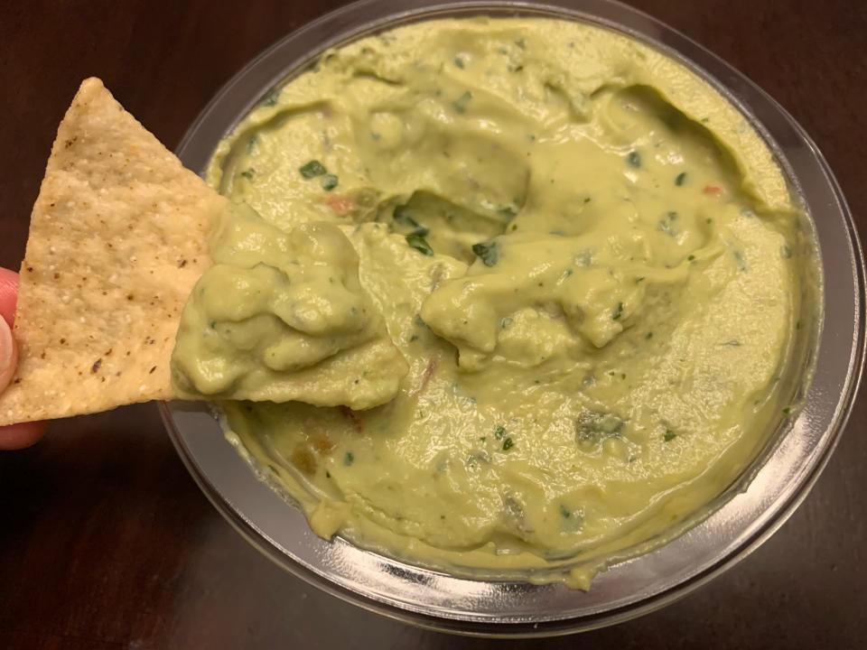 chip dipping into trader joe's chunky guacamole with greek yogurt