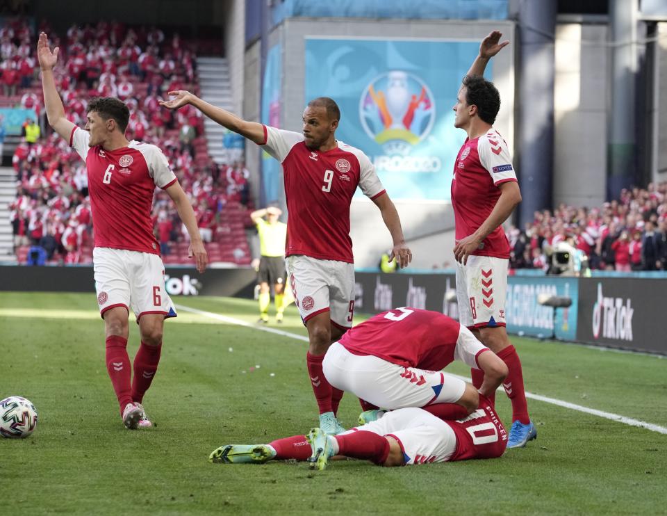 Denmark players run to Denmark's Christian Eriksen fallen on the ground during the Euro 2020 soccer championship group B match between Denmark and Finland at Parken Stadium in Copenhagen, Saturday, June 12, 2021. (AP Photo/Martin Meissner, Pool)