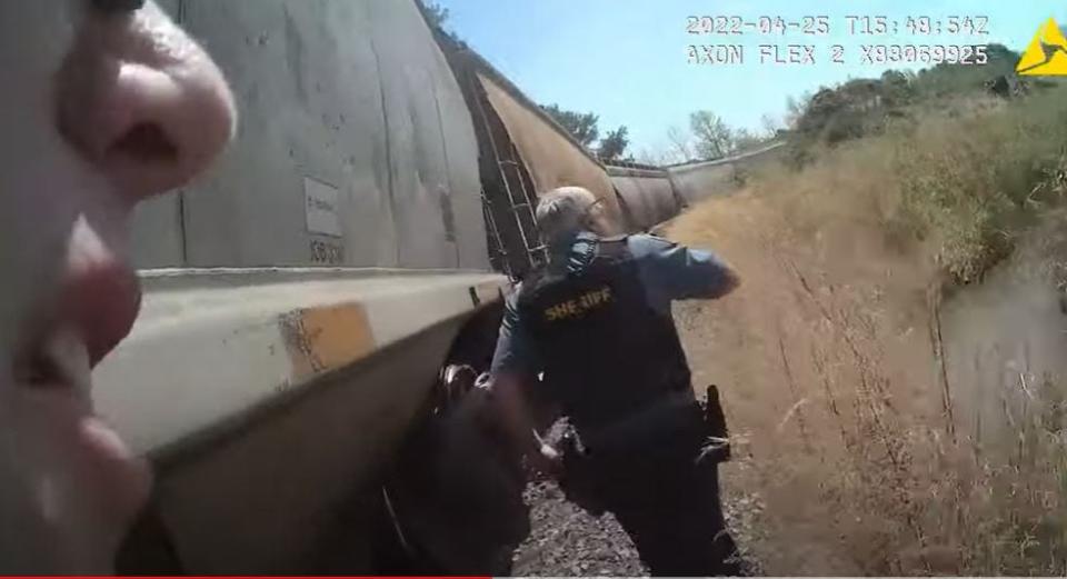 Law enforcement runs alongside a train in pursuit of William Robert Brink on April 25, 2022, in Westover.