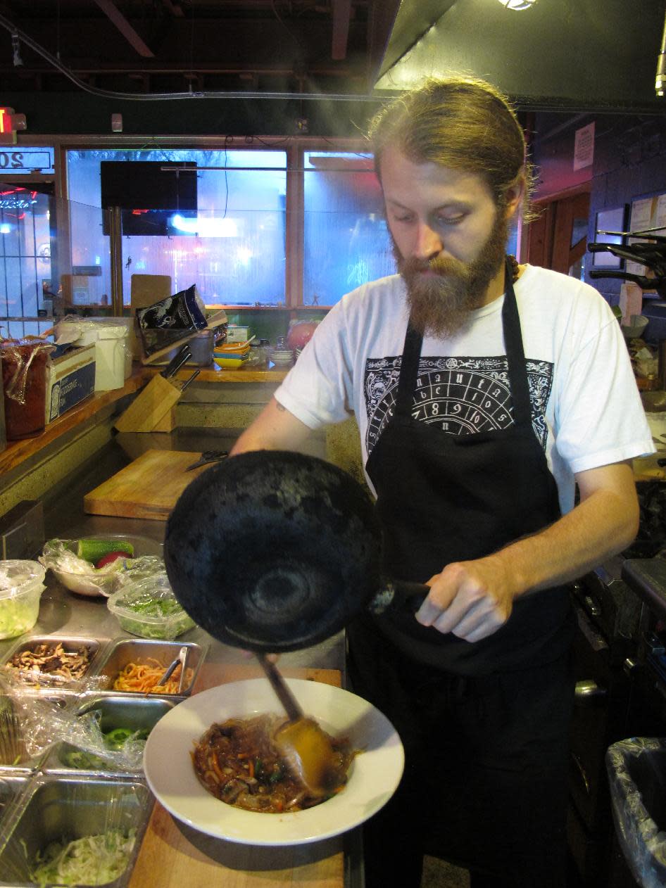 This Dec. 22, 2013 photo shows chef Adam Adkins serving a steaming-hot dish of sweet potato noodles, carrots, mushrooms and onions in a spicy sauce in the open kitchen at Crazy Noodle restaurant in Memphis, Tenn. (AP Photo/Adrian Sainz)