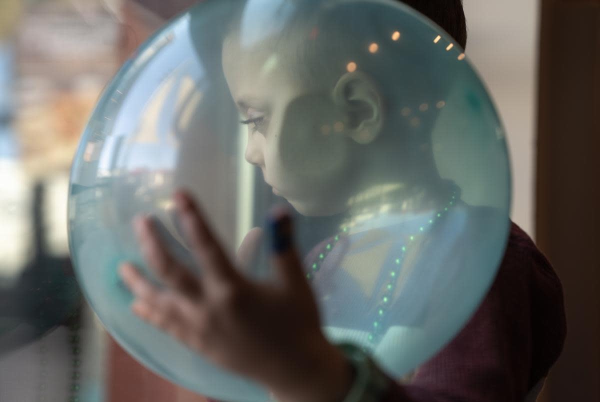 August Johansen looks through the glass door of the birthday venue while cradling a balloon on Dec. 9, 2023. He had inoperable brain cancer and depended on Medicaid to pay for full-time home nursing care from a private agency to help his mother take care of him throughout years of health crises. But in December, he became one of 810,000 children dropped from Texas’ Medicaid program in the previous five months, but was reinstated through his mother's efforts.