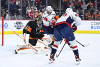 Philadelphia Flyers goaltender Carter Hart, left, makes a save on a shot from Washington Capitals' Martin Fehervary, right, during the third period of an NHL hockey game, Saturday, Feb. 26, 2022, in Philadelphia. (AP Photo/Derik Hamilton)