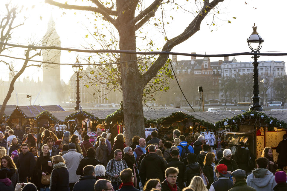 People walking and shopping at the authentically decorated wooden chalets of the Christmas Market promenade at the Southbank Centre London.