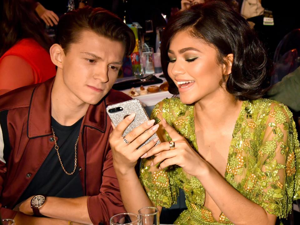 Zendaya showing Tom Holland her phone at the 2017 MTV Movie & TV Awards.