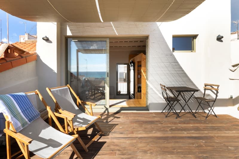 sunny apartment deck with lounge chairs and patio table and chairs