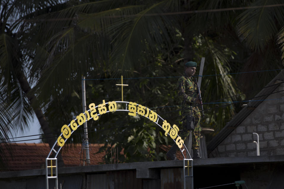 An officer of Special Task Force stands guard atop a building as funerals for Easter Sunday bomb blast victims take place at the Methodist burial ground in Negombo, Sri Lanka, April 23, 2019. (Photo: Gemunu Amarasinghe/AP)