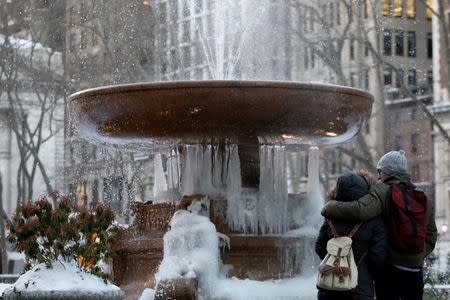 A couple embraces in front of an ice-covered fountain in Bryant Park in New York City, U.S. March 16, 2017. REUTERS/Brendan McDermid