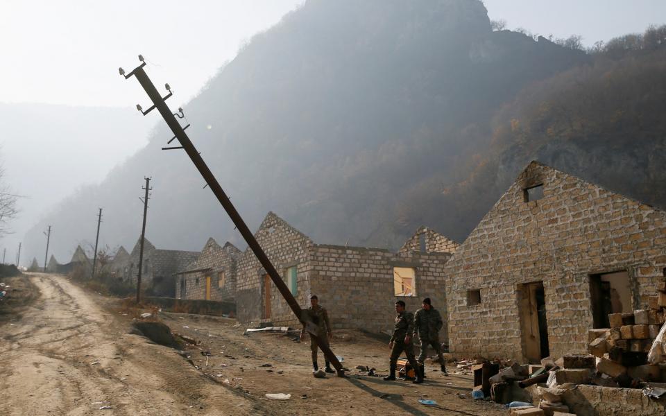 Ethnic Armenian soldiers destroy power poles in the village of Knaravan, which is soon to be turned over to Azerbaijan - Reuters