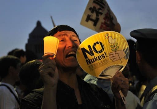 A protester holding a candle and a fan displaying the words "No Nukes" shouts slogans as he takes part in a rally in front of Japan's parliament, to demonstrate against the use of nuclear power following the 2011 Fukushima atomic crisis, in Tokyo