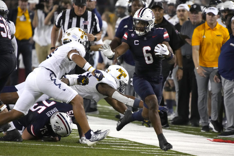 Arizona running back Michael Wiley (6) tries to get away from Northern Arizona defensive back Shawn Dourseau (0) during the first half of an NCAA college football game Saturday, Sept. 2, 2023, in Tucson, Ariz. (AP Photo/Rick Scuteri)