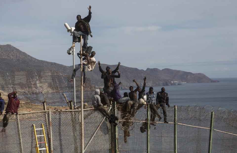 Sub-Saharan migrant shout slogans and wave as they sit on top of a metallic fence that divides Morocco and the Spanish enclave of Melilla onThursday April 3, 2014. Spanish and Moroccan police have thwarted a fresh attempt by dozens of African migrants to try to scale border fences to enter the Spanish enclave of Melilla. Thousands of sub-Saharan migrants seeking a better life in Europe are living illegally in Morocco and regularly try to enter Melilla in the hope of later making it to mainland Spain. (AP Photo/Santi Palacios)