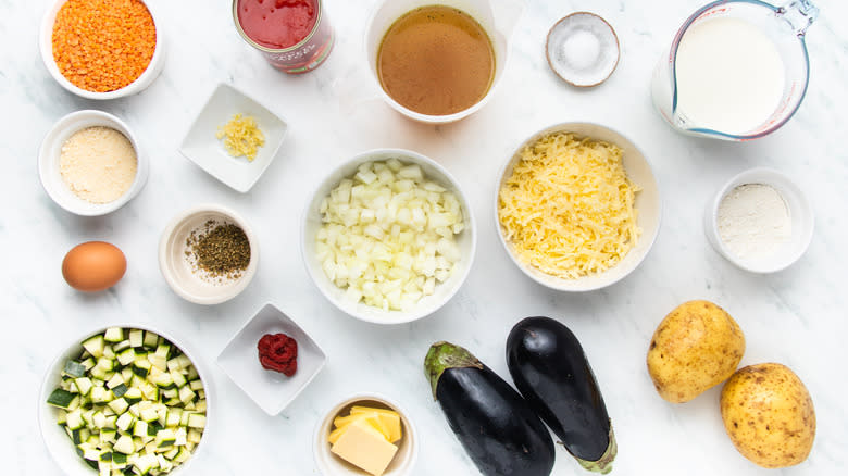 Lentil moussaka ingredients laid out on marble counter