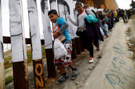 <p>Members of a caravan of migrants from Central America walk next to the border fence between Mexico and the U.S., before a gathering in a park and prior to preparations for an asylum request in the U.S., in Tijuana, Mexico April 29, 2018. (Photo: Edgard Garrido/Reuters) </p>