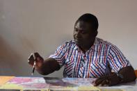 Savadogo, a security consultant and former Burkinabe gendarme, points to a regional map in Ouagadougou