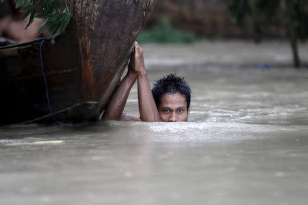 A boy moves his boat in a flooded village outside Zalun Township, Irrawaddy Delta, Myanmar, August 6, 2015. REUTERS/Soe Zeya Tun