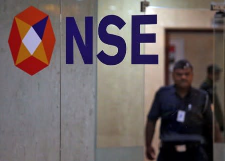 A security guard walks past the logo of the National Stock Exchange inside its building in Mumbai