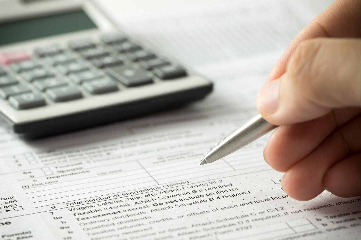 hand with pen on tax return and calculator