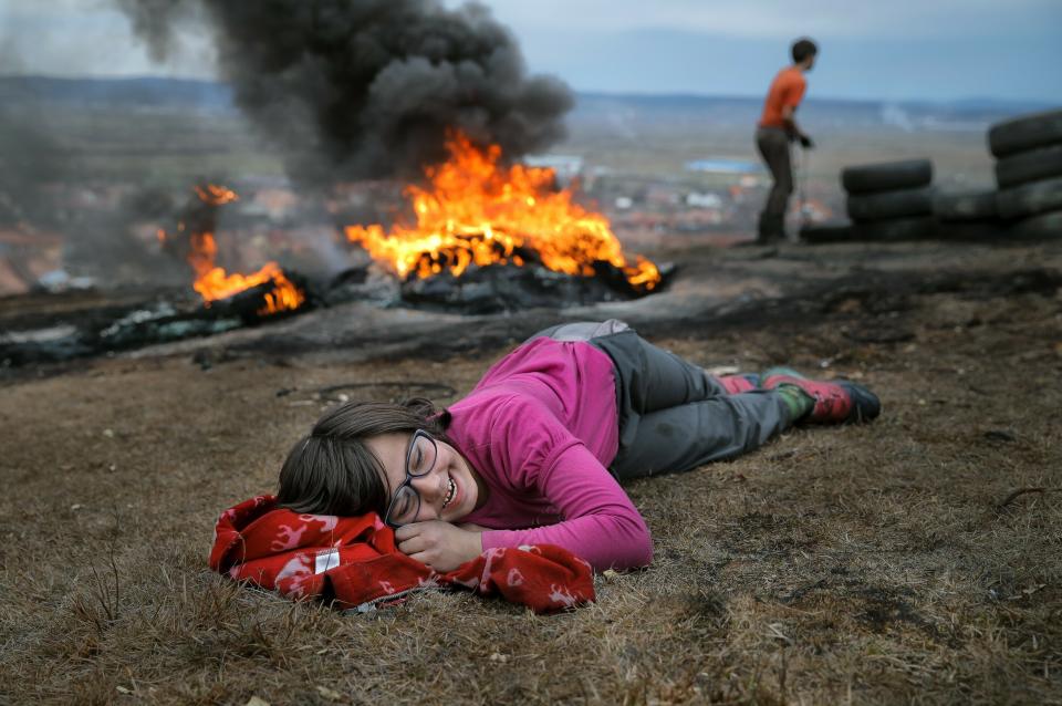 In this photo taken on Sunday, March 10, 2019, a little girl laughs during a ritual marking the upcoming Clean Monday, the beginning of the Great Lent, 40 days ahead of Orthodox Easter, on the hills surrounding the village of Poplaca, in central Romania's Transylvania region. Romanian villagers burn piles of used tires then spin them in the Transylvanian hills in a ritual they believe will ward off evil spirits as they begin a period of 40 days of abstention, when Orthodox Christians cut out meat, fish, eggs, and dairy. (AP Photo/Vadim Ghirda)