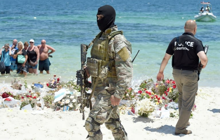 A Tunisian special force officer and a policeman patrol the beach as tourists take part in a ceremony on July 3, 2015, in memory of those killed the previous week by a jihadist gunman in the popular resort of Port el Kantaoui