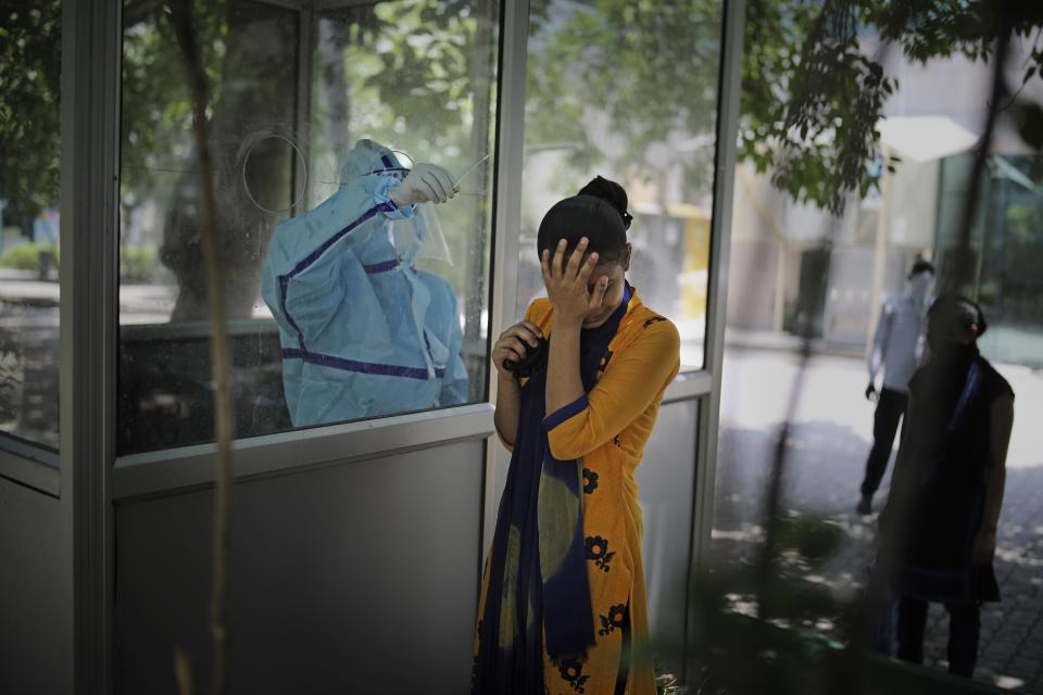 FILE - In this Tuesday, June 16, 2020 file photo a woman reacts after getting a nasal swab taken to test for the coronavirus in Noida, on the outskirts of New Delhi, India. (AP Photo/Altaf Qadri, File)