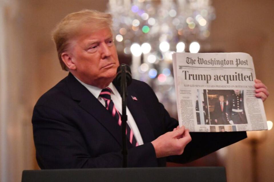 President Donald Trump flaunts a newspaper headlines about his impeachment acquittal during a news conference in the White House earlier this month. | NICHOLAS KAMM/AFP via Getty