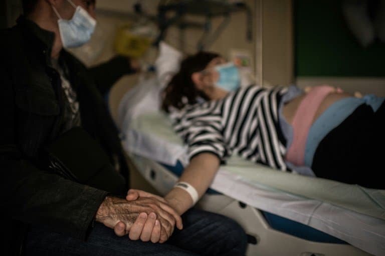 Un homme portant un masque de protection tient la main de sa femme enceinte à la maternité des Diaconesses à Paris, le 17 novembre 2020 - Martin BUREAU © 2019 AFP