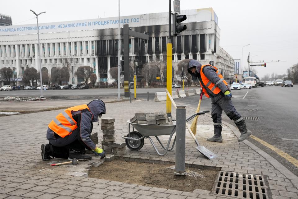 Municipal workers repair the sidewalk at the city hall building in the central square in Almaty, Kazakhstan, Tuesday, Jan. 11, 2022. The president of Kazakhstan announced Tuesday that a Russia-led security alliance will start pulling out its troops from the country in two days after completing its mission. Life in Almaty, which was affected with the violence the most, started returning to normal this week, with public transport resuming operation and malls reopening. (AP Photo)