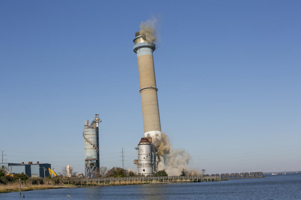 The smokestack at the former B.L. England Generating Station, a coal and oil burning power plant in Upper Township, N.J., is toppled during a control demolition on Thursday, October 26, 2023. The site will be redeveloped as a mixed-use residential and commercial project, and a nearby electrical substation will be used to connect New Jersey's soon-to-come offshore wind farms with the electrical grid. (AP Photo/Ted Shaffrey)