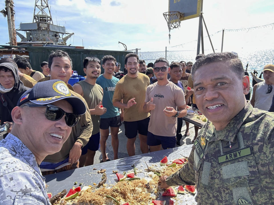 In this handout photo provided by the Armed Forces of the Philippines PAO, Philippine military chief, General Brawner, right, and Vice Admiral Alberto Carlos, left, Commander of the AFP's Western Command shares a meal with Filipino marines and navy personnel stationed aboard the long-marooned BRP Sierra Madre at the Second Thomas Shoal, locally known as Ayungin Shoal, at the disputed South China Sea on Sunday Dec. 10, 2023. The Philippine military chief said Monday he was with Filipino forces aboard a supply boat when it was blasted with a water cannon and surrounded and bumped by Chinese coast guard ships over the weekend in the disputed South China Sea. (Armed Forces of the Philippines PAO via AP)