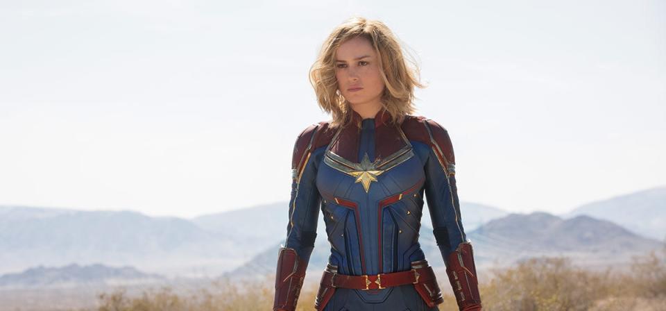 A movie still of superhero Captain Marvel in a blue and red outfit with a gold star.