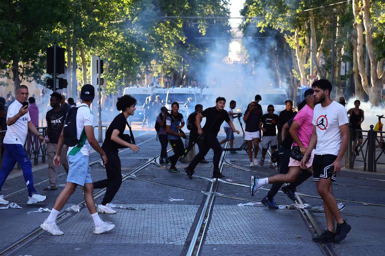 Manifestantes huyen de los cartuchos de gas lacrimógeno lanzados durante los enfrentamientos con la policía en Marsella, sur de Francia, el 1 de julio de 2023, tras una cuarta noche consecutiva de disturbios en Francia por la muerte de un adolescente a manos de la policía.