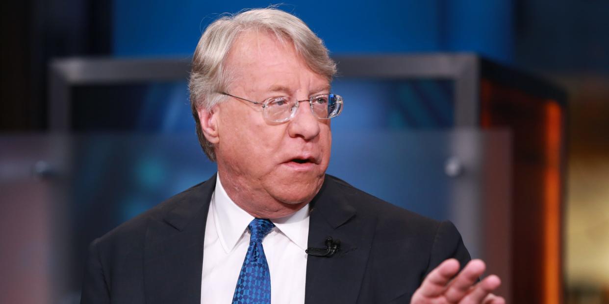 Jim Chanos speaking with his hand raised while wearing a black suit with a blue tie.