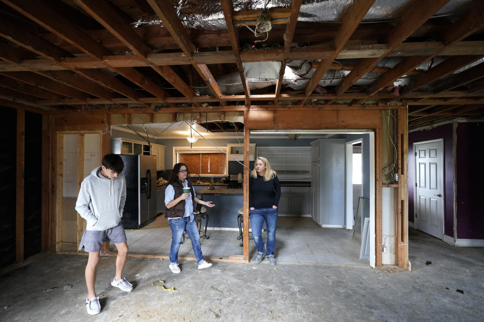 Christi, center, and Brandy Monticello, walk through their heavily damaged and gutted home, with their son Brennan Ash, in the aftermath of Hurricane Laura and Hurricane Delta, in Lake Charles, La., Friday, Dec. 4, 2020. (AP Photo/Gerald Herbert)