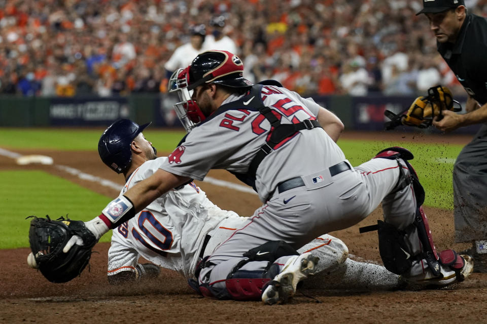 Houston Astros' Yuli Gurriel scores past Boston Red Sox catcher Kevin Plawecki on a sacrifice flay by Jose Altuve during the eighth inning in Game 1 of baseball's American League Championship Series Friday, Oct. 15, 2021, in Houston. (AP Photo/Tony Gutierrez)