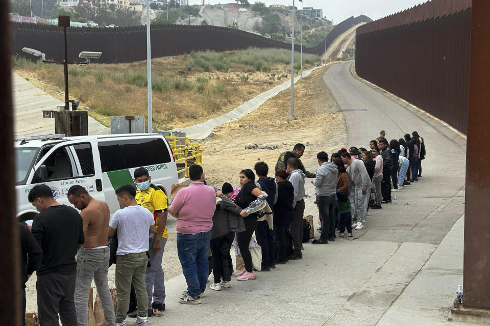 Migrantes que buscan asilo se forman mientras esperan ser procesados luego de cruzar la frontera desde México, el miércoles 5 de junio de 2024, en San Diego, California. (AP Foto/Eugene Garcia)