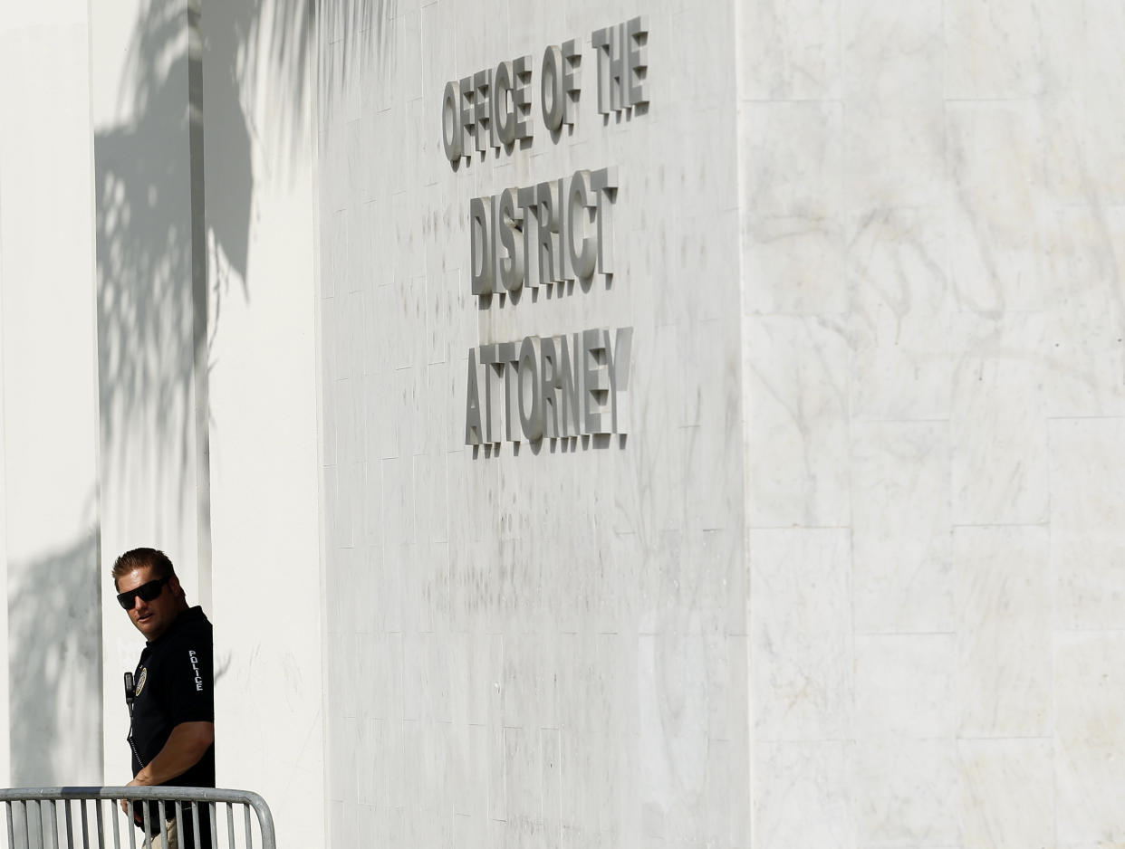A policeman looks out of the Orange County District Attorney's building. (Photo: Mike Blake / Reuters)
