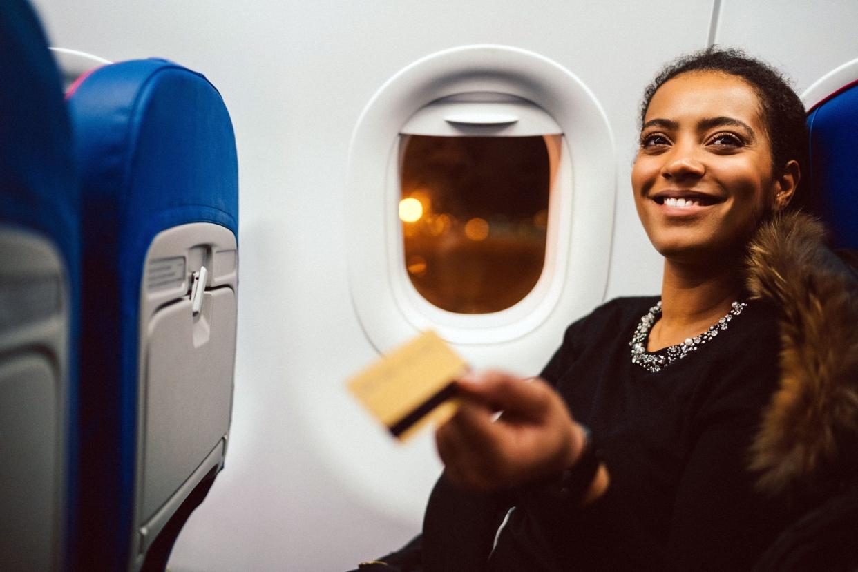 woman smiling on airplane handing card to flight attendant