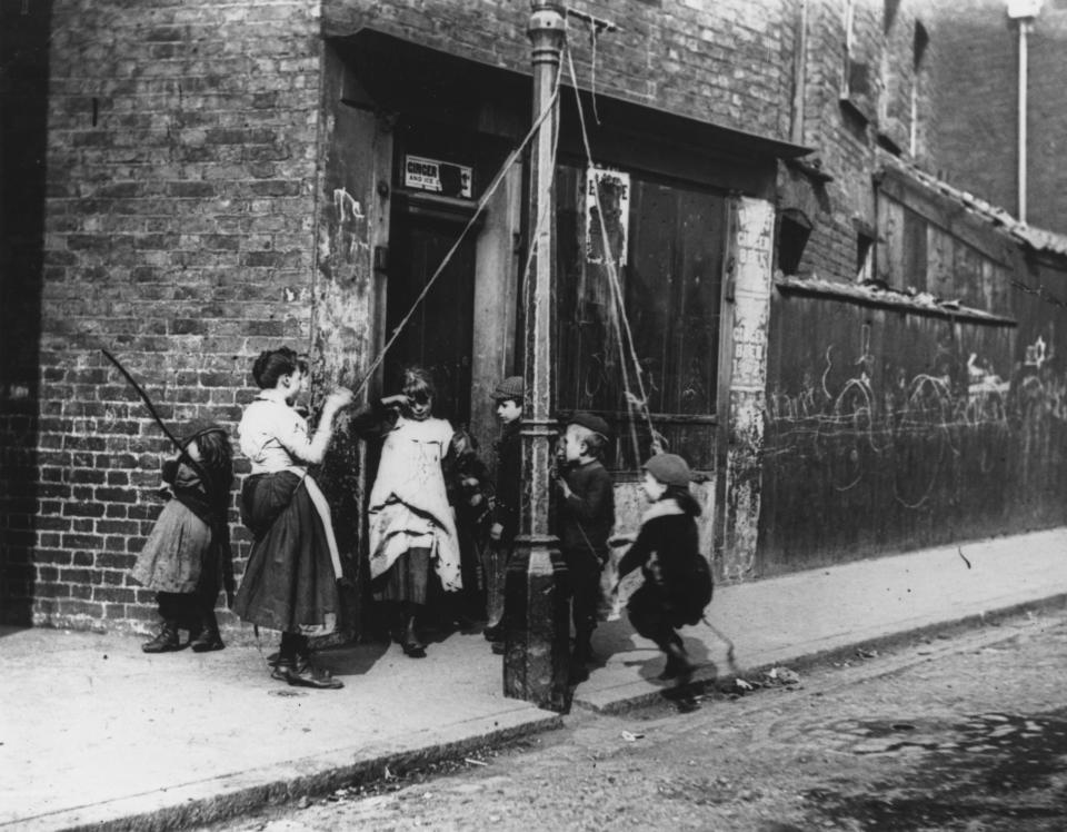 Circa 1892: Children living in the slums improvise a lamppost and some rope as a swing.   (Photo by Paul  Martin/Getty Images)