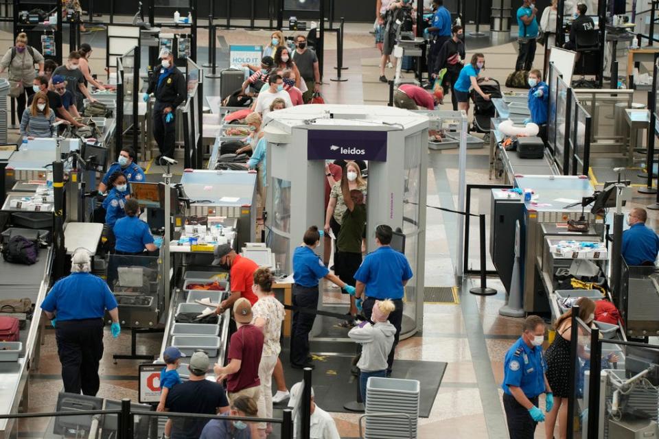 Travelers wear face coverings in the line for the south security checkpoint in the main terminal of Denver International Airport on Aug. 24, 2021, in Denver. The Biden administration is detailing its new international COVID-19 air travel polices, which will include exemptions for kids and new federal contact tracing requirements.