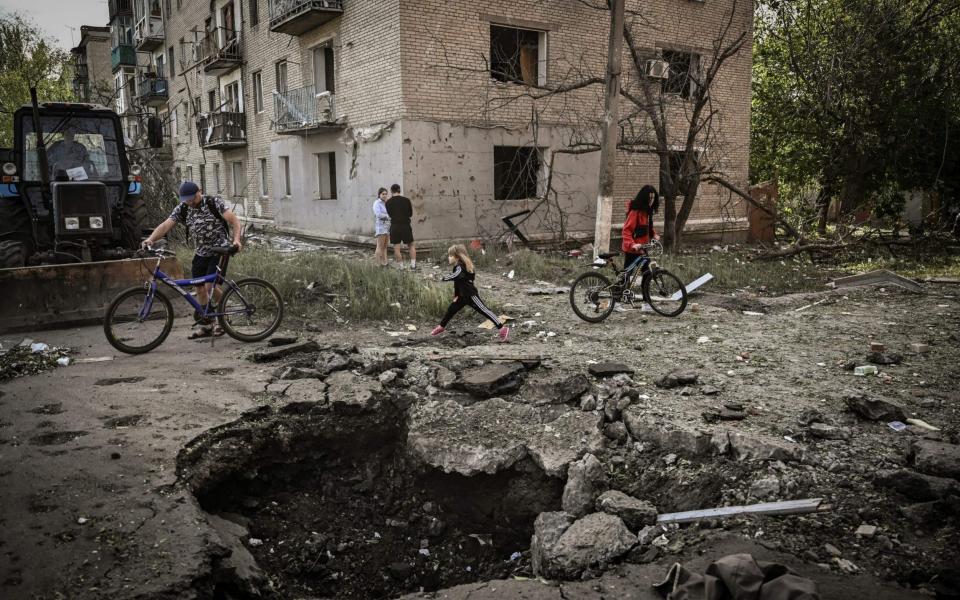 A young girl walks by a crater in front of a damaged appartment building after a strike in the city of Slovyansk at the eastern Ukrainian region of Donbas on May 31, 2022, amid Russian invasion of Ukraine. - Photo by ARIS MESSINIS / AFP