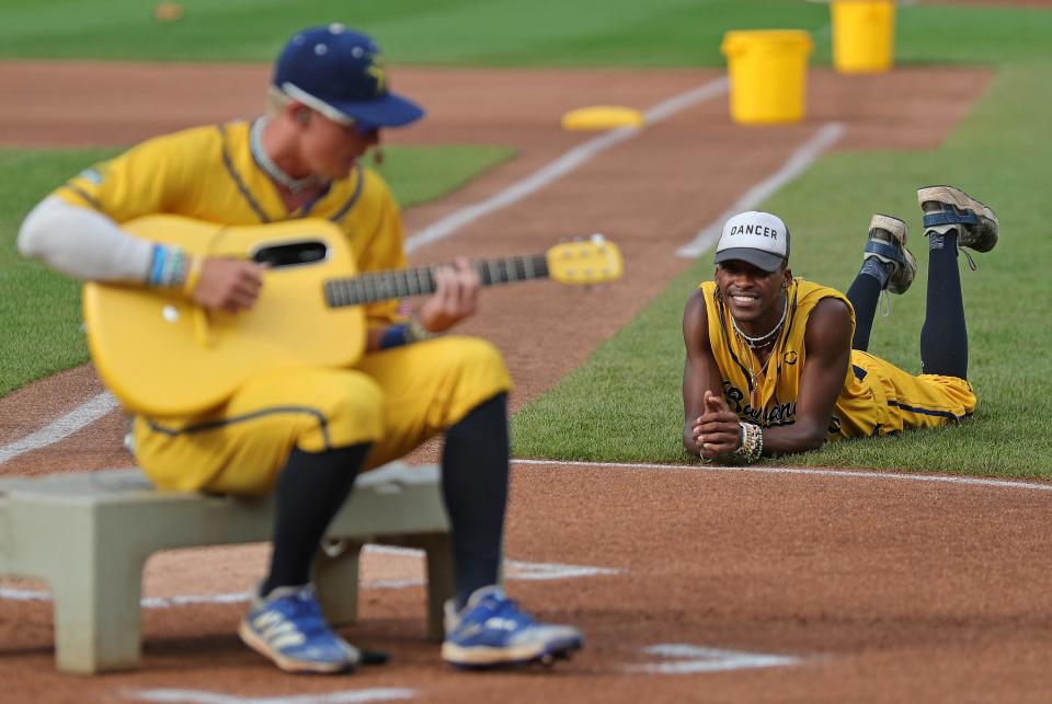 Savannah Bananas first base coach Maceo Harrison, right, listens as a player performs a tune at home plate during the Savannah Bananas' World Tour at Canal Park, Monday, July 3, 2023, in Akron, Ohio.