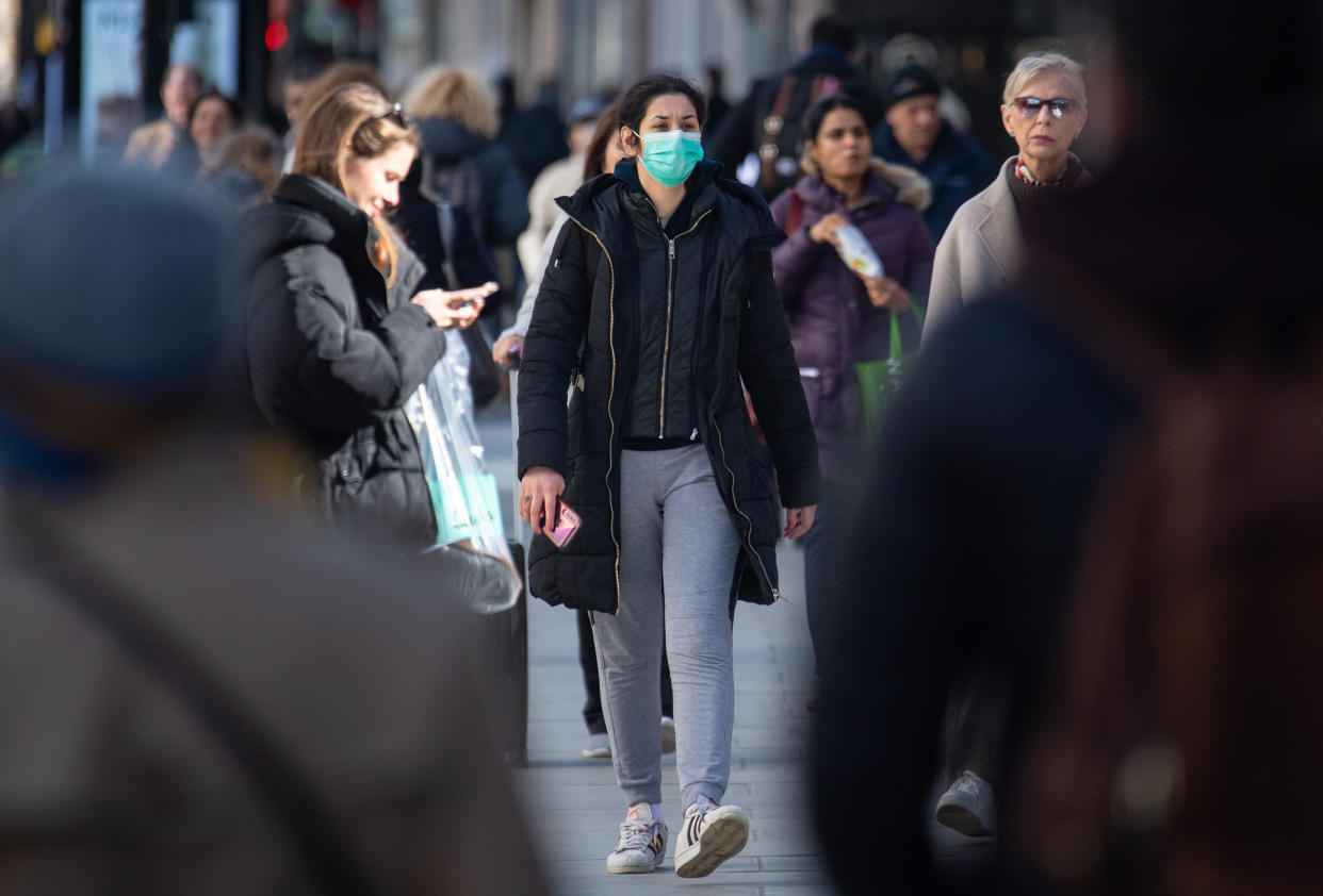 A woman wearing protective face masks on Oxford Street, central London. On Thursday evening, an older patient, reported to be a woman in her 70s, became the first person in the UK to die after being diagnosed.