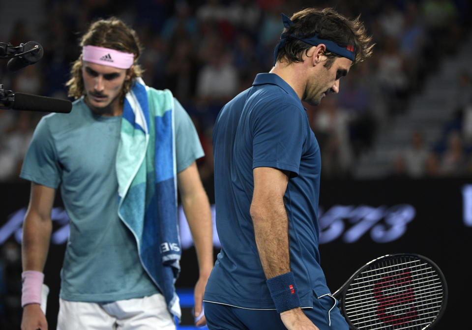 El tenista suizo Roger Federer (derecha) y el griego Stefanos Tsitsipas caminan hacia sus sillas durante un descanso en su partido de octavos del final del Abierto de Australia, en Melbourne, Australia, el 20 de enero de 2019. (AP Foto/Andy Brownbill)