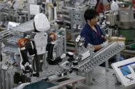 A humanoid robot works side by side with employees in the assembly line at a factory of Glory Ltd., a manufacturer of automatic change dispensers, in Kazo, north of Tokyo, Japan, July 1, 2015. REUTERS/Issei Kato