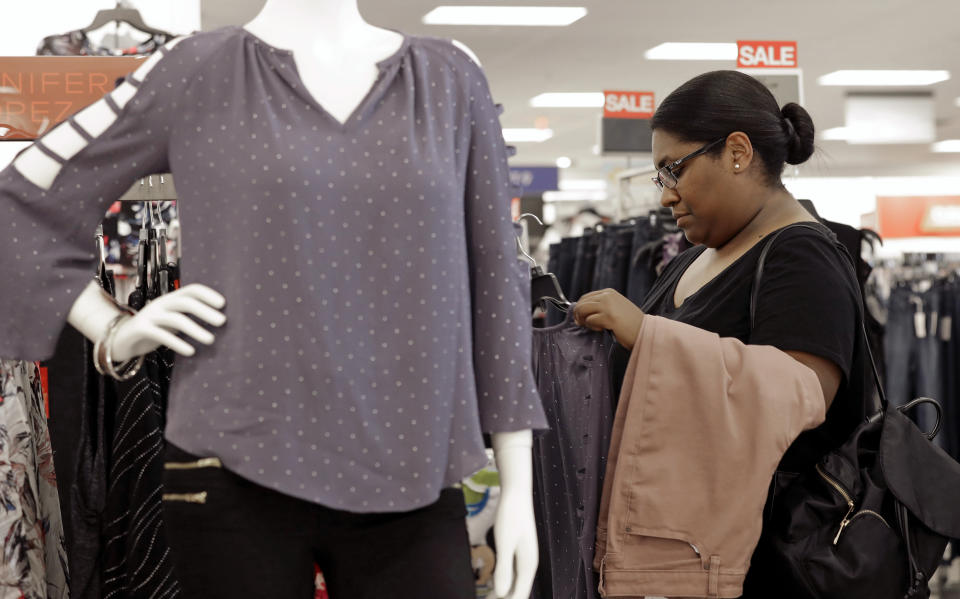 In this Tuesday, Aug. 28, 2018, photo Heather Camacuari, of Charlotte, N.C., shops for clothing at a Kohl's store in Concord, N.C. Many kinds of chains have posted strong sales, both online and at stores. A booming economy, which has shoppers spending more freely, and companies' own efforts in trying to Amazon-proof their business is driving people’s mood to spend. (AP Photo/Chuck Burton)